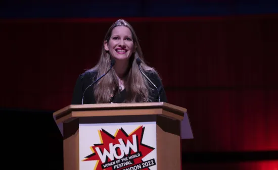 The author Laura Bates stands at a lectern at the WOW Festival