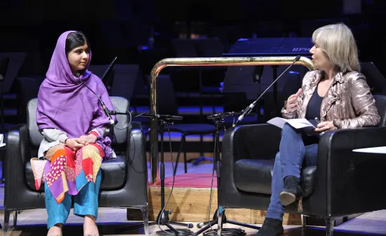 Malala Yousafzai and Jude Kelly sit on a stage