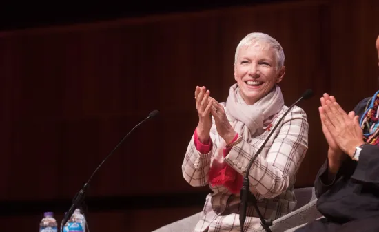 Two women sit on stage clapping