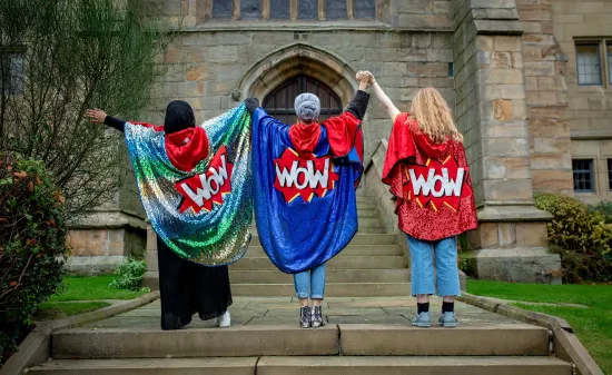 Three women wearing capes saying WOW